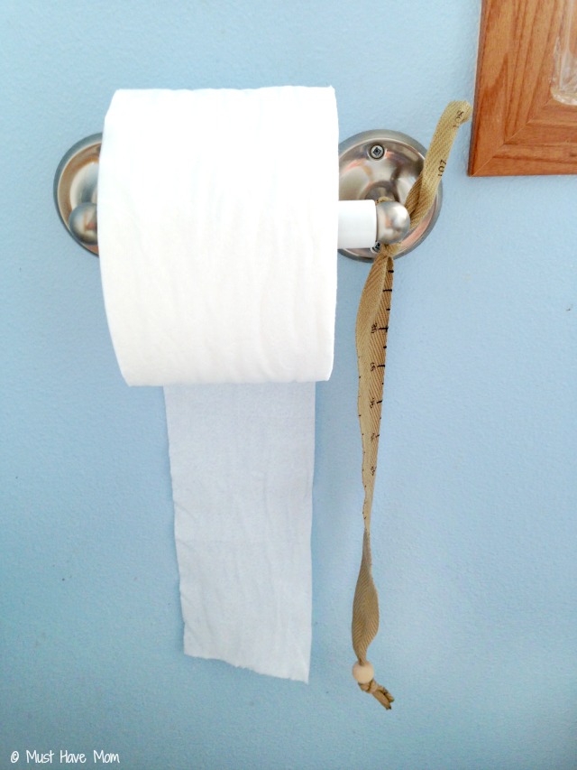 Toddler girl potty training holding toilet paper in bathroom Stock