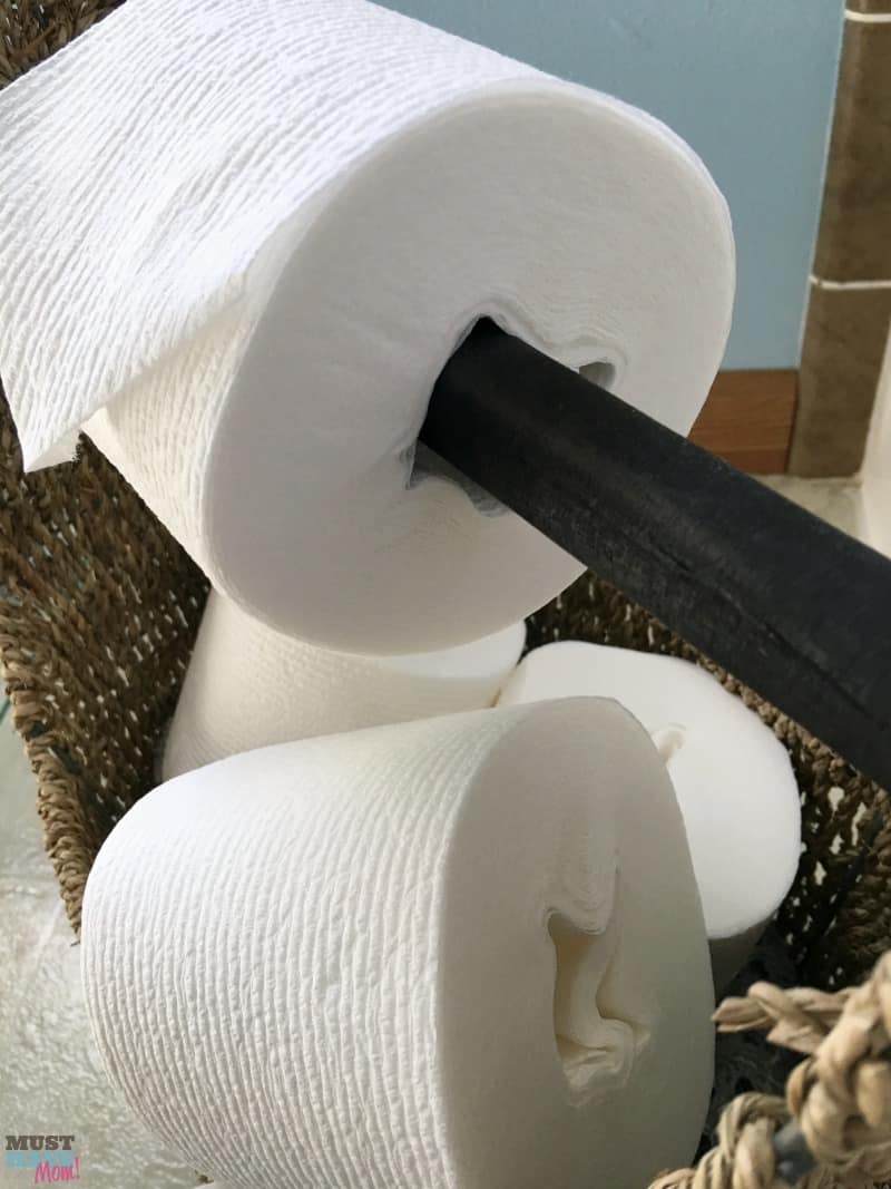 DIY toilet paper holder idea! Use a wicker basket with a wood handle as a toilet paper holder and fill the basket with extra toilet paper rolls. Works with tube free toilet paper rolls too!