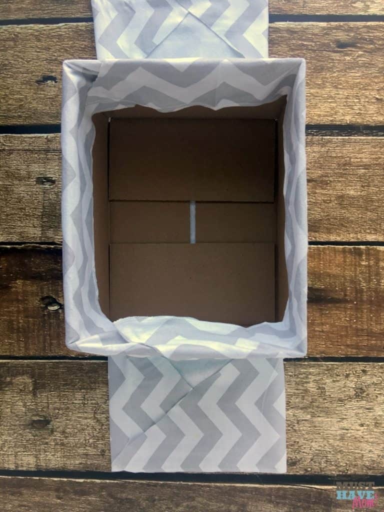 How to turn a cardboard box (like a diaper box) into a fabric covered basket! No sew method of making a fabric lined basket to compliment nursery decor! Make it for free with upcycled supplies!