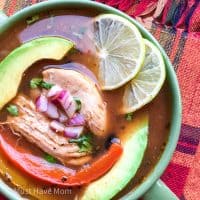 chicken fajita soup in a bowl with avocado, limes and garnish